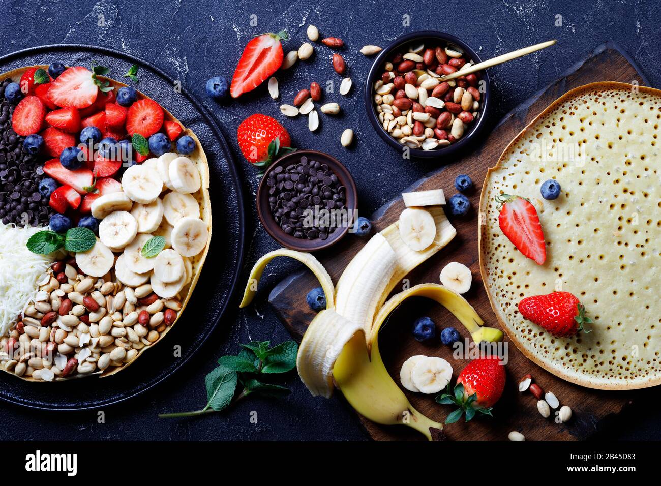 Manis de martabak ou pancake de terang bulan indonésien avec des chips de chocolat, des arachides, des fraises, des bleuets, des bananes, du fromage, sur un fond sombre Banque D'Images