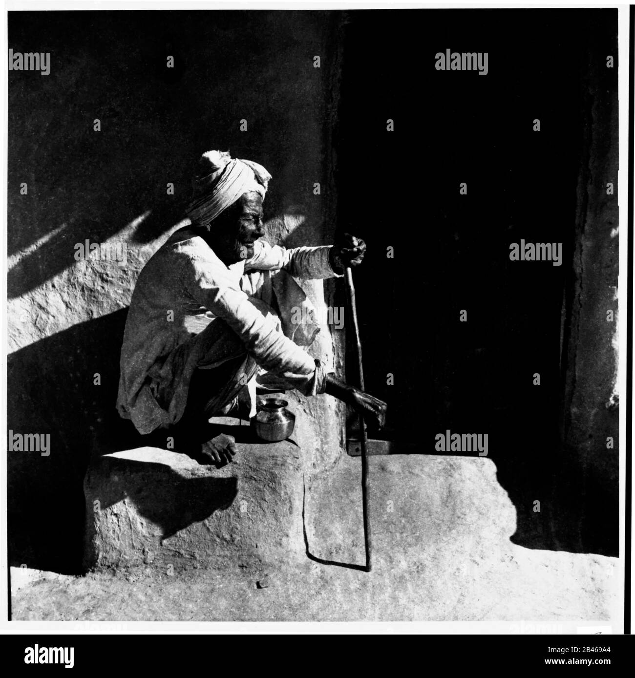 Vieux homme assis en équilibre avec un bâton de marche, Uttar Pradesh, Inde, Asie, 1956, ancienne image millésime 1900 Banque D'Images