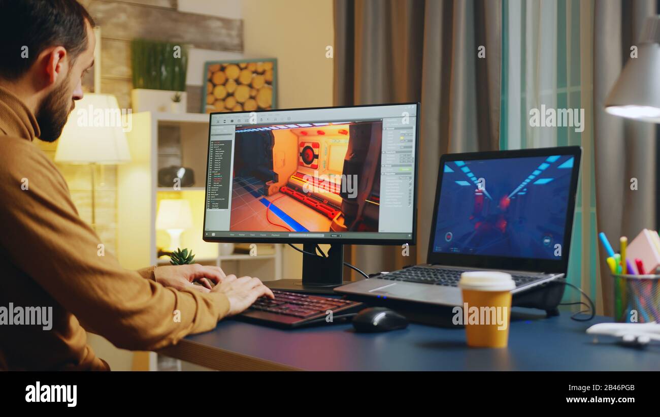 Développeur de jeu masculin tapant sur le clavier tout en développant un nouveau niveau du jeu. Banque D'Images