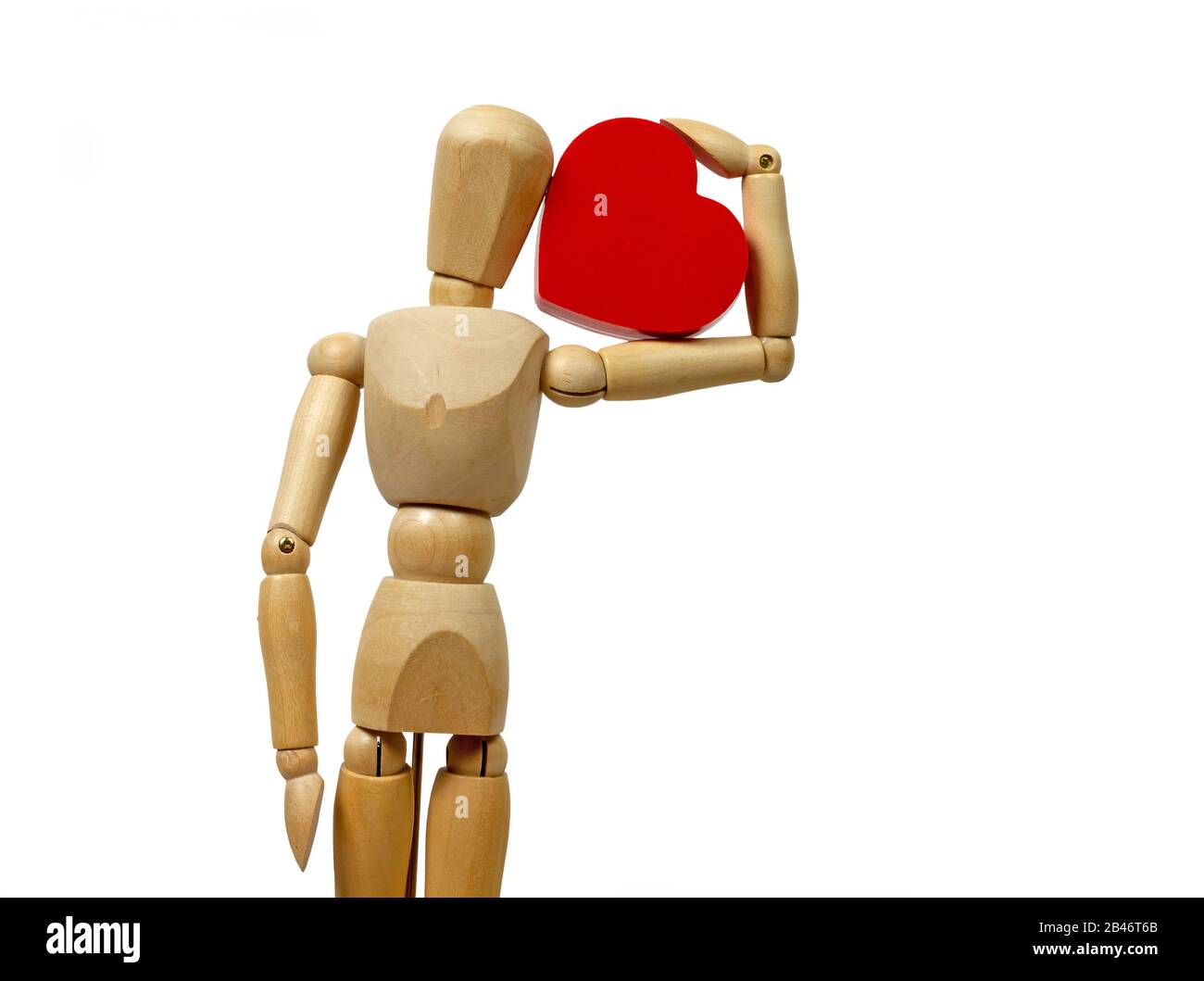 Mannequin en bois isolé, tenant un grand cœur rouge sur un fond blanc Banque D'Images