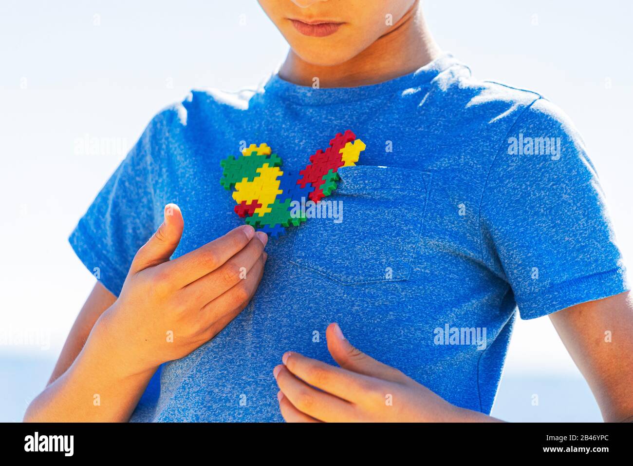 Garçon tenant le puzzle coloré cœur de conscience de l'autisme dans ses mains Banque D'Images