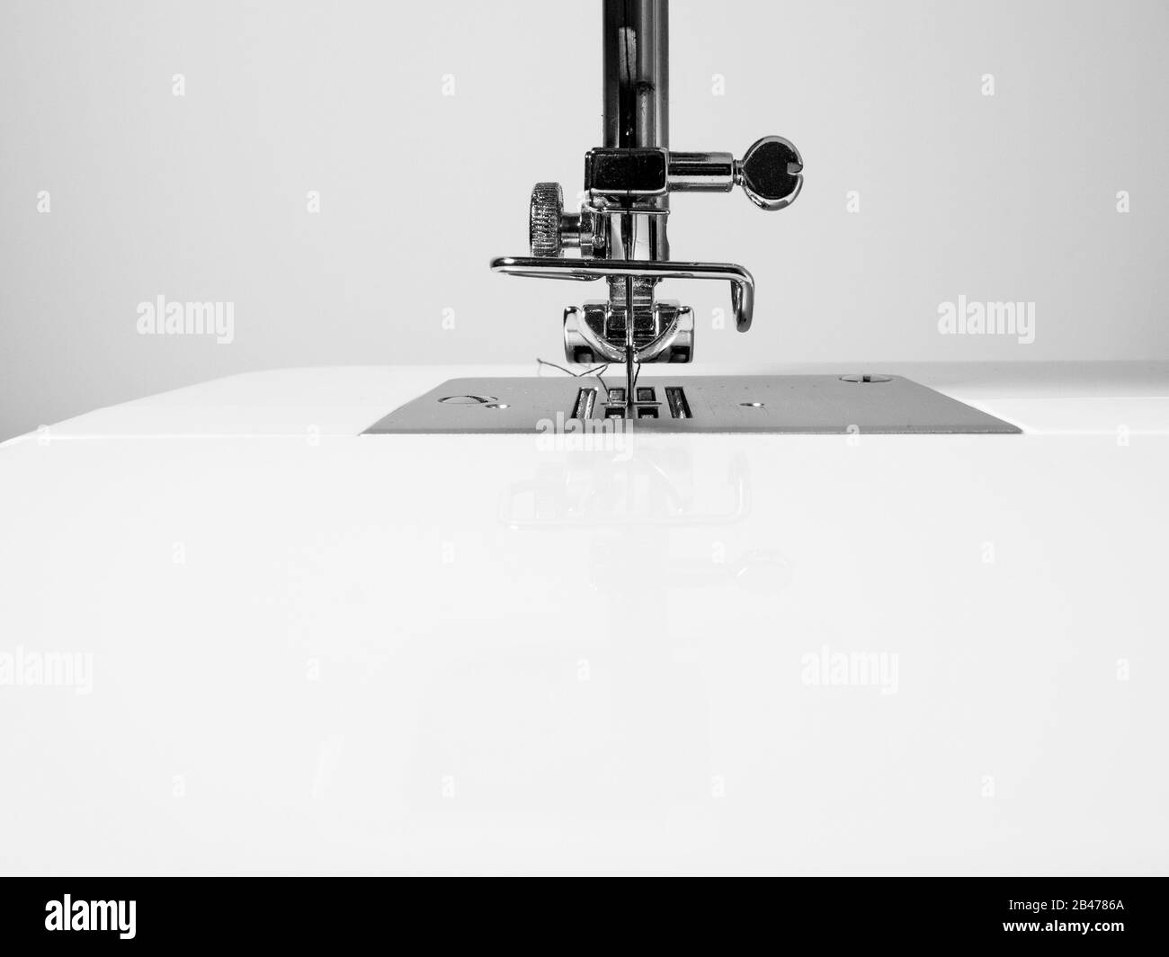 Détail machine à coudre sur un fond de mur blanc. Espace de copie, noir et blanc. Concept d'artisanat. Banque D'Images