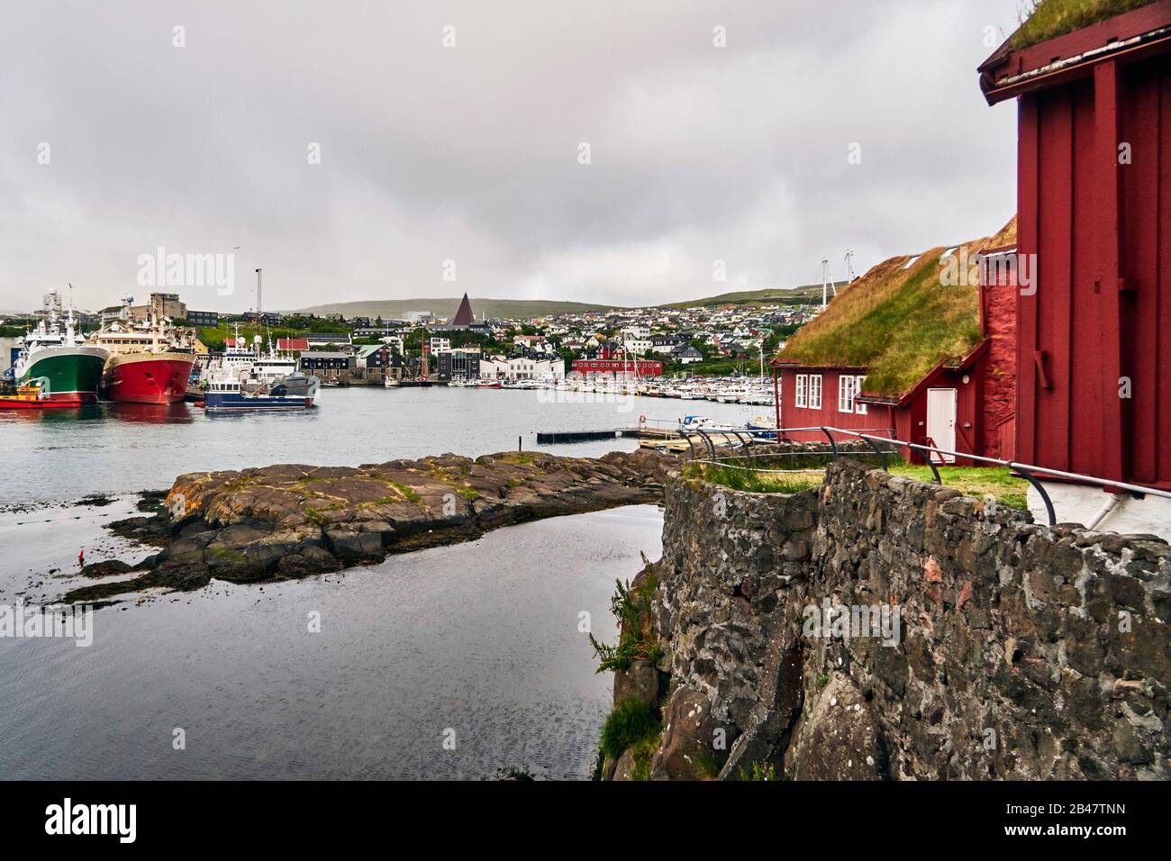 Danemark, Torshavn. 12 juillet 2018. Tórshavn, la capitale et la plus grande ville des îles Féroé, est située dans la partie sud de la côte est de Streymoy. Tinganes est l'emplacement historique et la partie centrale de Tórshavn. De nombreuses maisons en bois de Tinganes ont été construites aux XVIe et XVIIe siècles et ont la couleur rouge typique ainsi que le toit en herbe, ce qui est très commun sur les îles Féroé. Banque D'Images