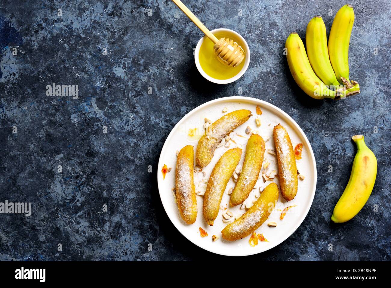Bananes fritures sur fond blanc sur fond de pierre bleue avec espace texte  libre. Délicieux dessert à base de bananes poêlées dans un style asiatique.  Vue sur le dessus, plat Photo Stock -