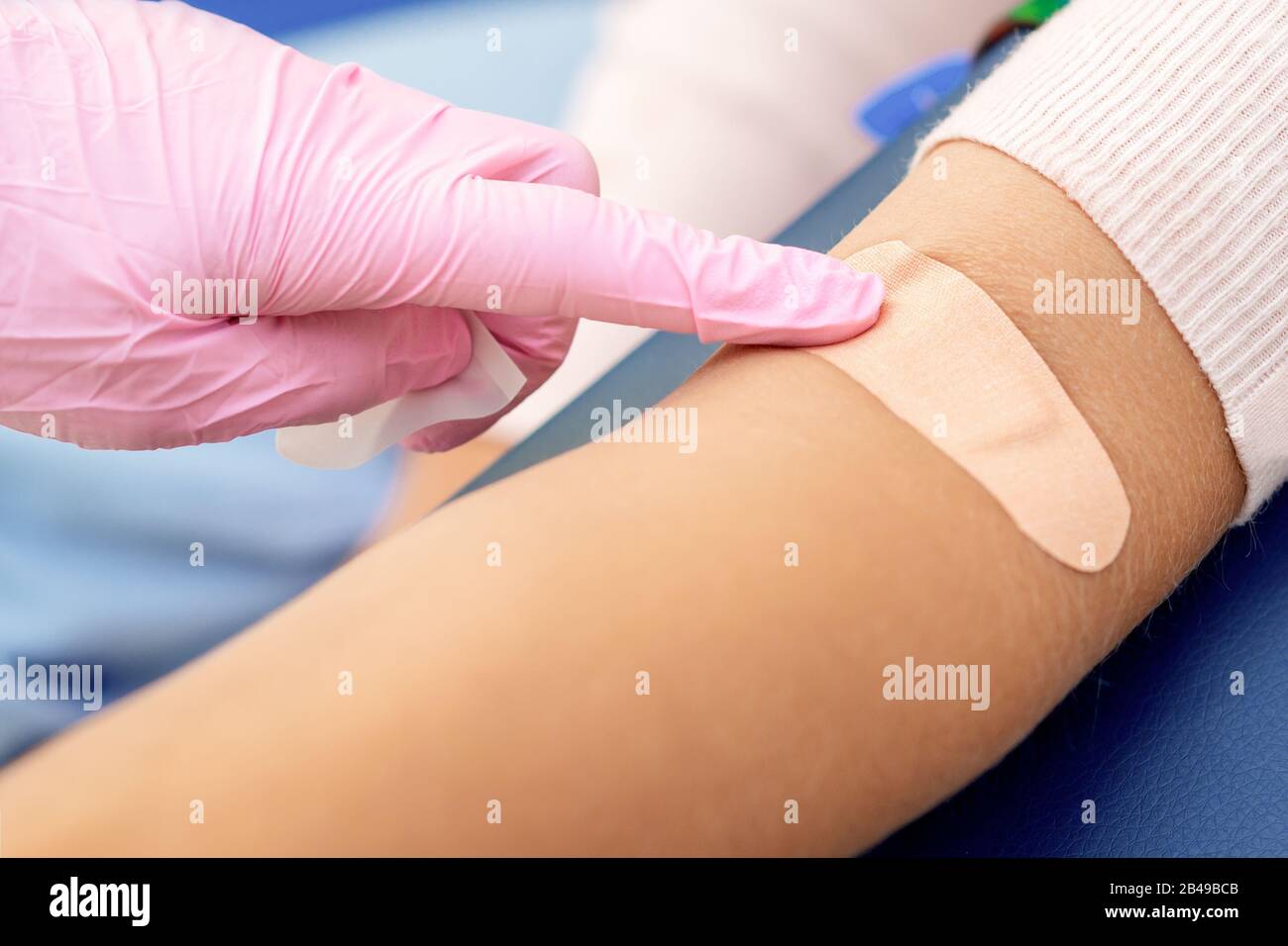 Le médecin en gants de protection en caoutchouc colle un bandage adhésif  sur le bras Photo Stock - Alamy