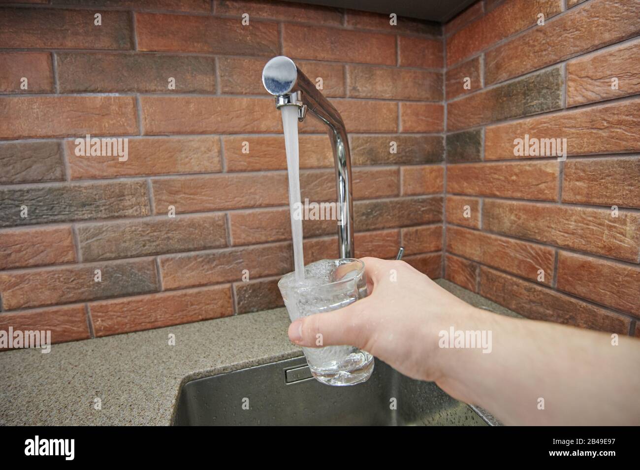 Verser de l'eau dans le verre du robinet. Thème eau potable Banque D'Images