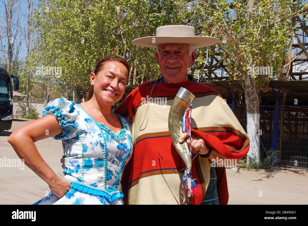 Touriste masculin dans le poncho et chapeau de cow-boy chilien; Huaso; tenant corne, femme en robe de danse, camp d'entraînement Huaso; Amérique du Sud; Santiago; Chili; Sud A Banque D'Images
