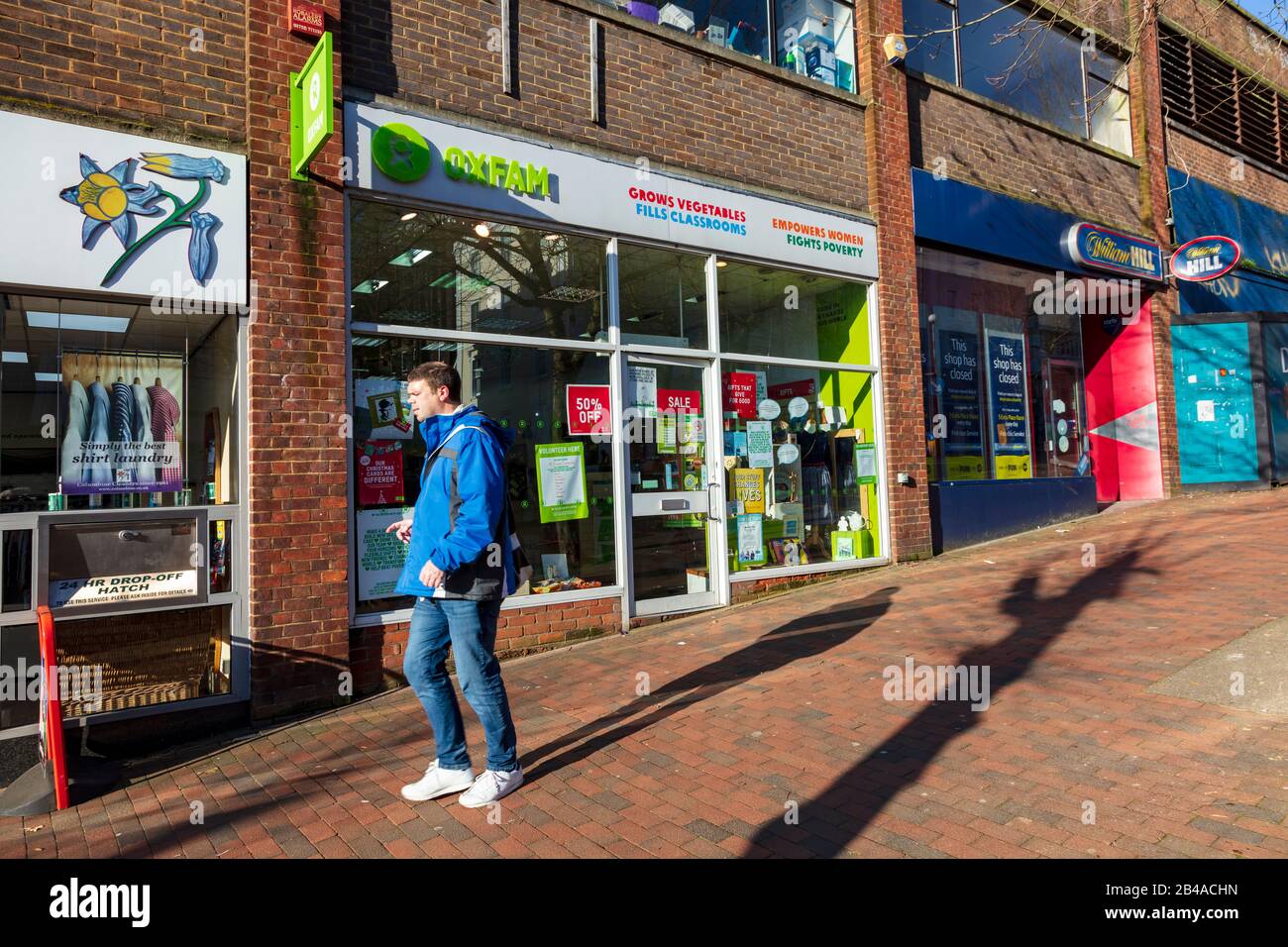 Un homme passe devant la boutique de charité d'Oxfam sur Mount Pleasant Road, Tunbridge Wells, à côté d'une librairie William Hill, Kent, Royaume-Uni Banque D'Images