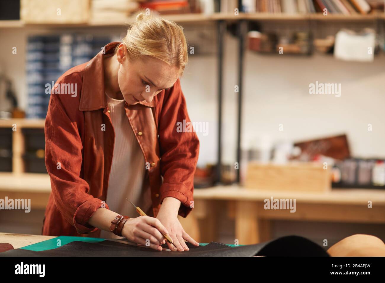 Hotizontal moyenne piqûre de jeune femme concentrée debout à table travaillant dans un atelier d'artisanat moderne Banque D'Images