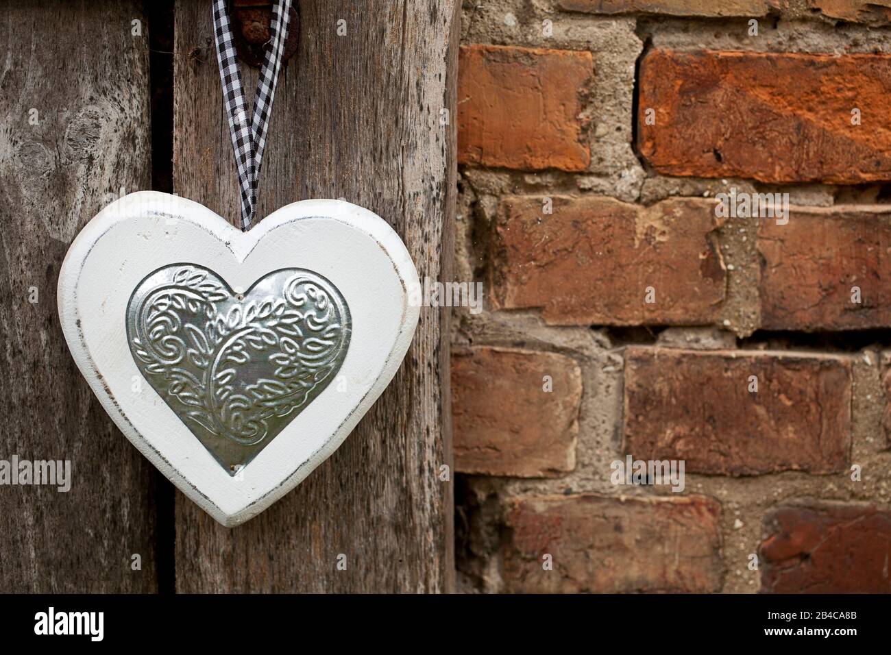 Coeur en bois avec application argentée accrochée sur l'ancienne porte de grange avec espace de copie Banque D'Images