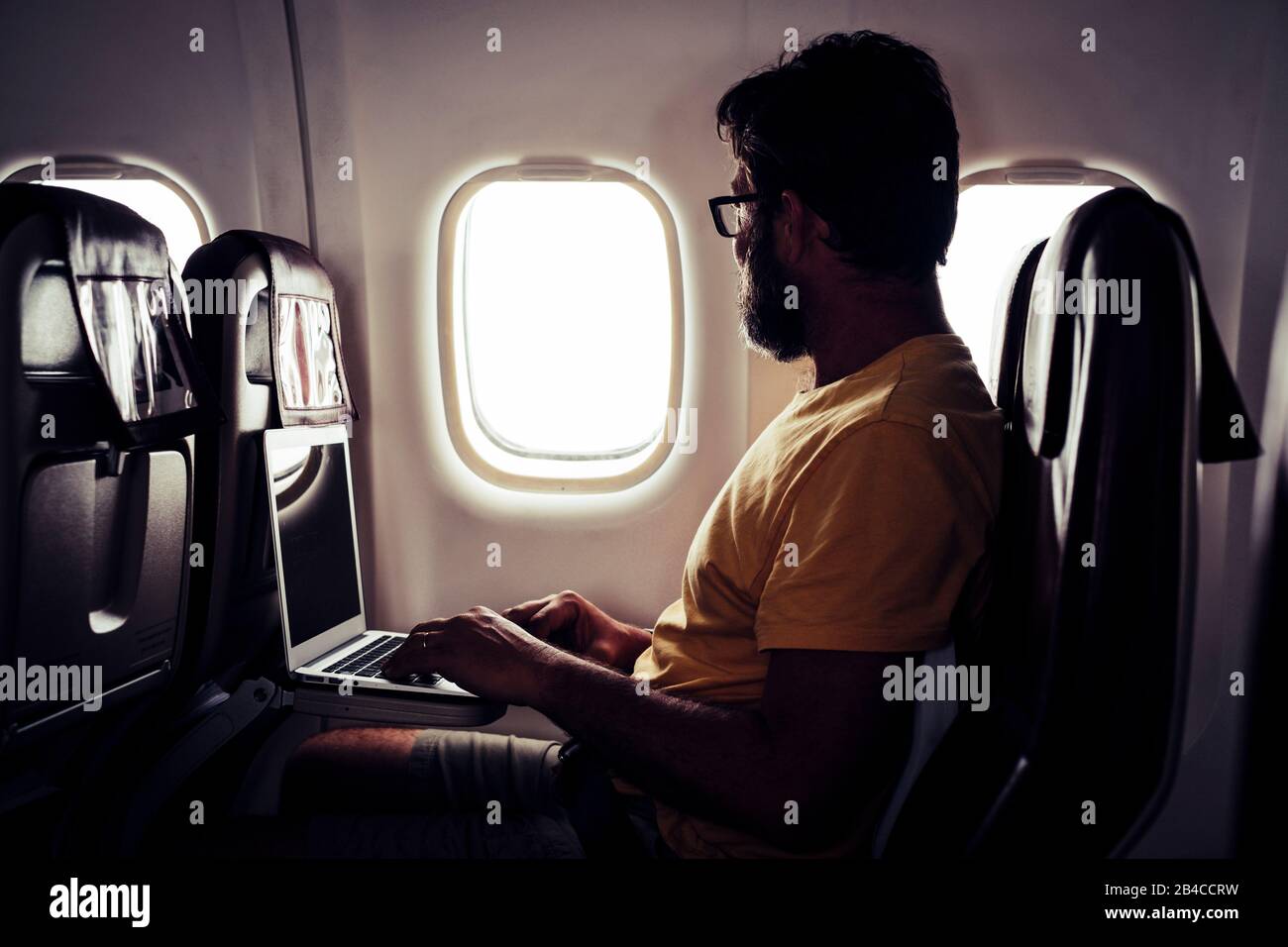 Homme de voyage barbu adulte assis à l'intérieur de l'avion et de vol à destination - ordinateur avec connexion internet wifi à bord concept de service - voyageur les gens de voler style de vie Banque D'Images