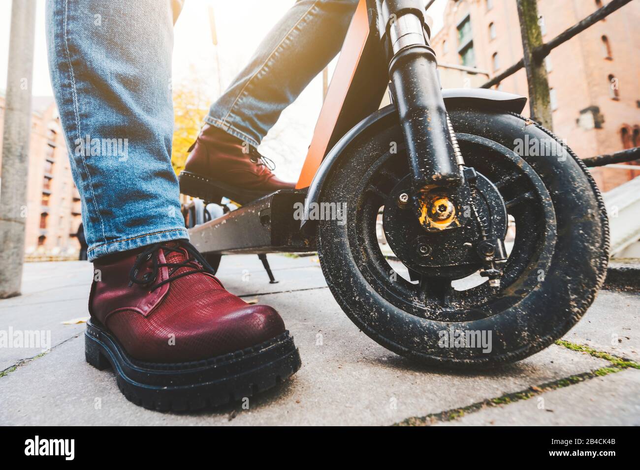 Gros plan sur le scooter électrique de kick ou le scooter électronique et bottes pour femmes sur le pavé - tendance e-mobilité ou micro-mobilité. Speicherstadt, Hambourg, Allemagne, Euro Banque D'Images