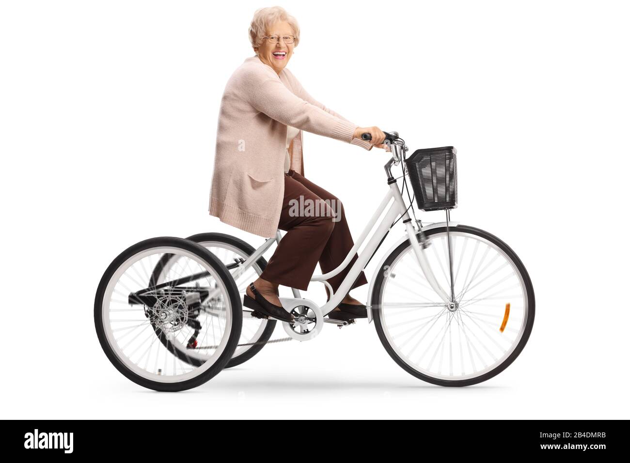 Femme senior qui monte dans un tricycle et riant isolée sur fond blanc Banque D'Images