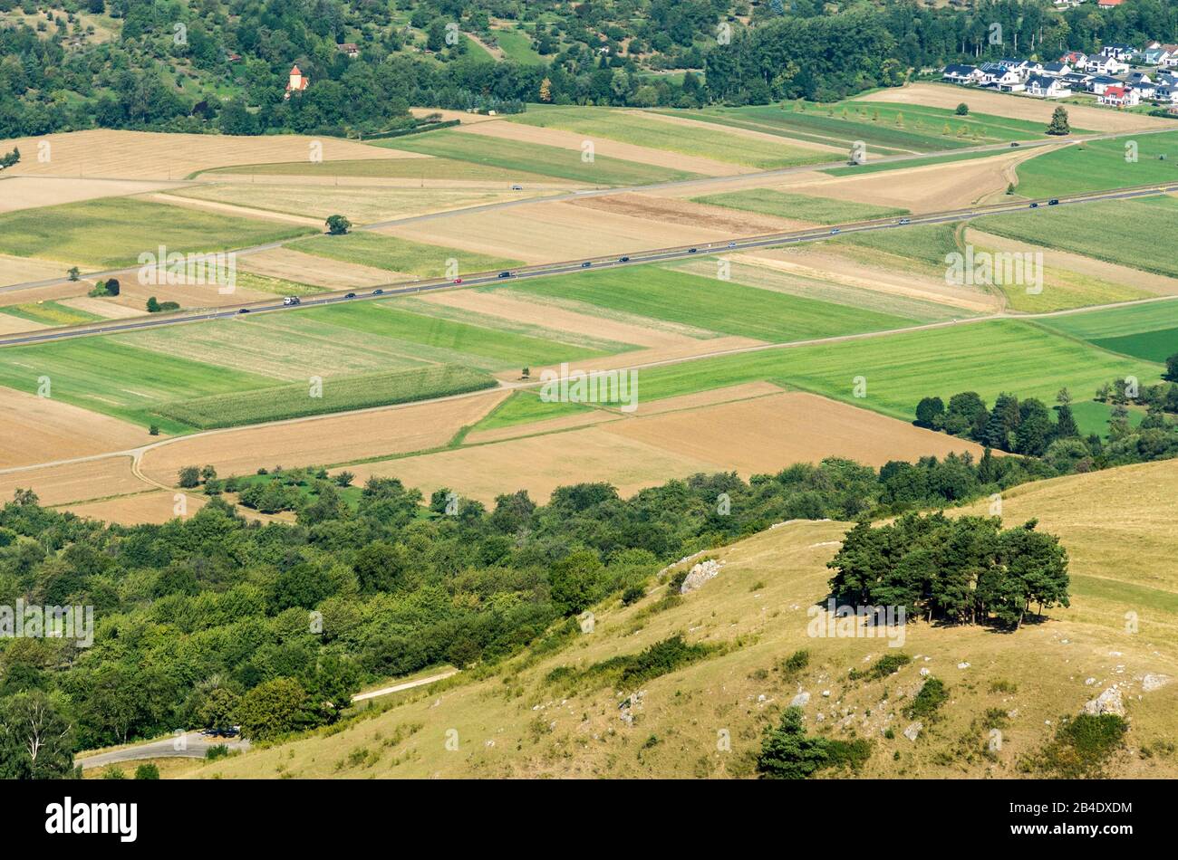 Allemagne, Bade-Wurtemberg, Owen, Sibyllenspur dans la vallée de Lenninger Lauter entre Owen et Dettingen. Dites « Sibylle du Teck ». Au cours de la croissance des plantes Sibyllenspur est un peu plus forte et apparaît donc plus sombre que la végétation environnante. Sibylle Lane = rayures diagonales plus foncées sous la voiture rouge. Banque D'Images