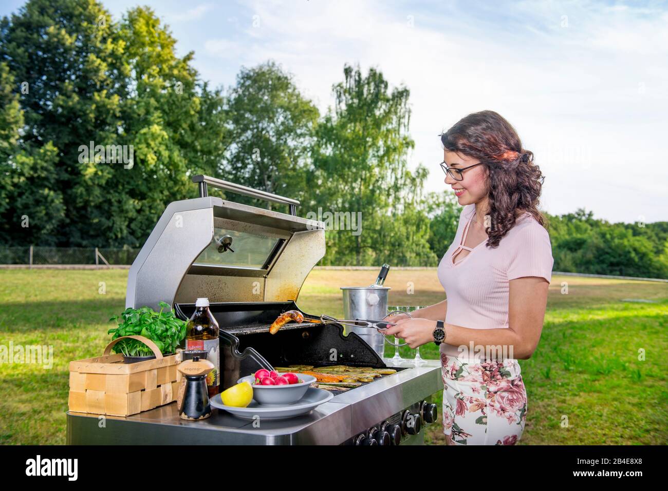 Jeunes femmes grils dans le jardin, barbecue Banque D'Images