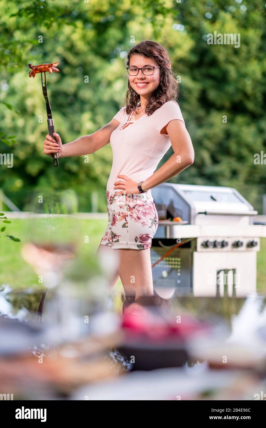 Jeune femme au barbecue dans le jardin, barbecue, rosen Banque D'Images