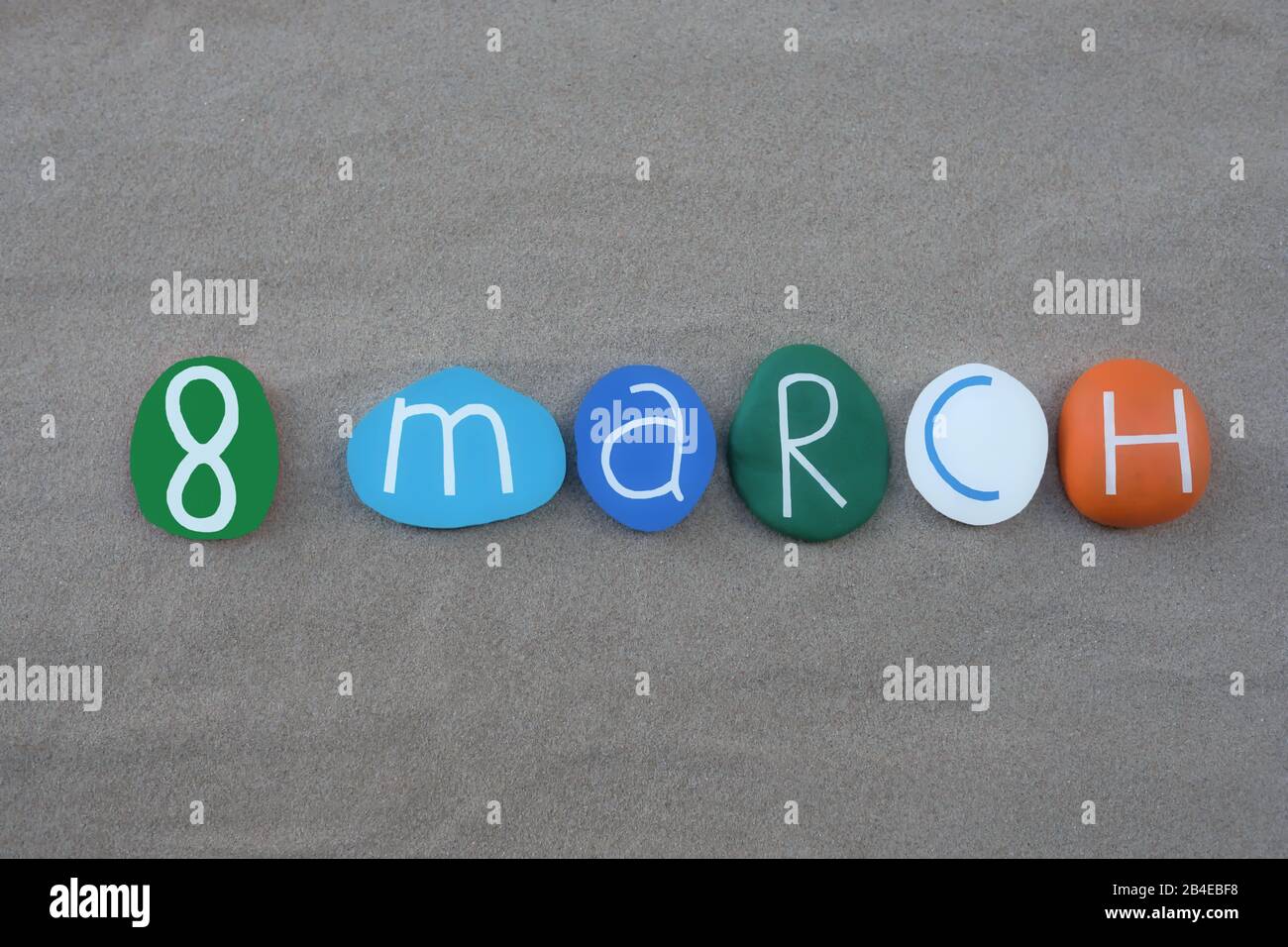 8 mars, date du calendrier composée de pierres colorées et sculptées sur du sable vert Banque D'Images