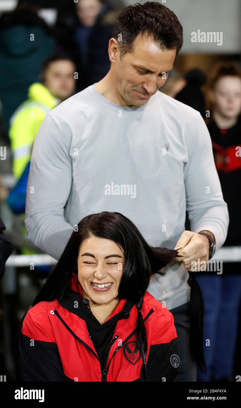 St Helens Saints la capitaine de femme Emily Rudge a ses cheveux coupés par l'ancien capitaine Paul Sculpthorpe à l'aide De Little Princesses Trroust, avant le match de la Super League Betfred au stade Totalement Wicked, St Helens. Banque D'Images