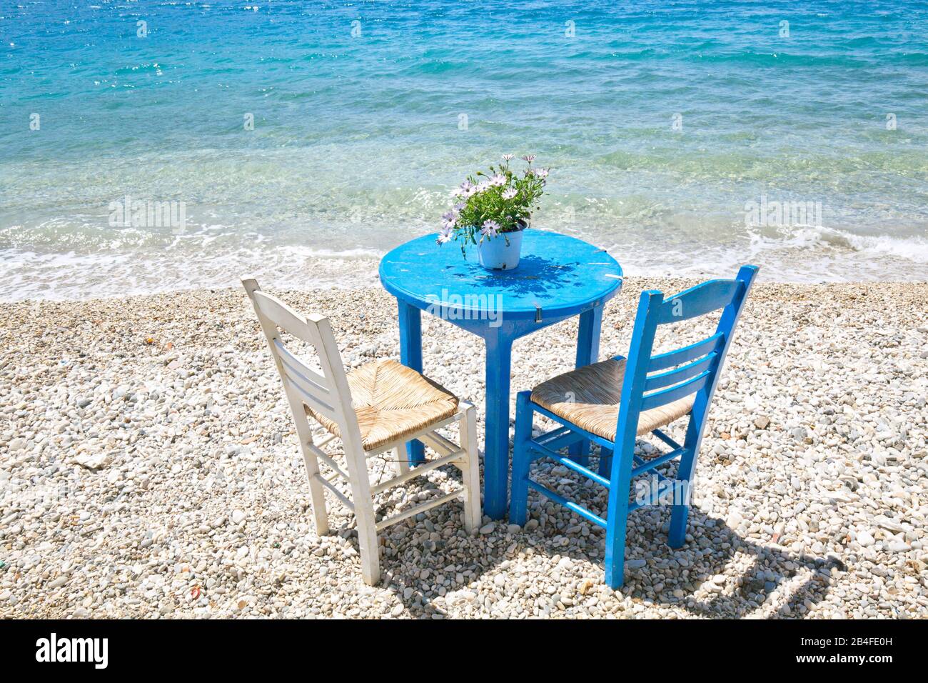 Chaise bleue et table d'une taverne sur la plage de galets de Mitikas,  Aetolia Acarnia, Grèce Photo Stock - Alamy