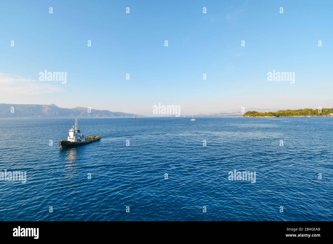 Un petit bateau pilote traverse la mer Égée vers un bateau de croisière (non visible) juste à côté de l'île de Corfou, Grèce. Banque D'Images