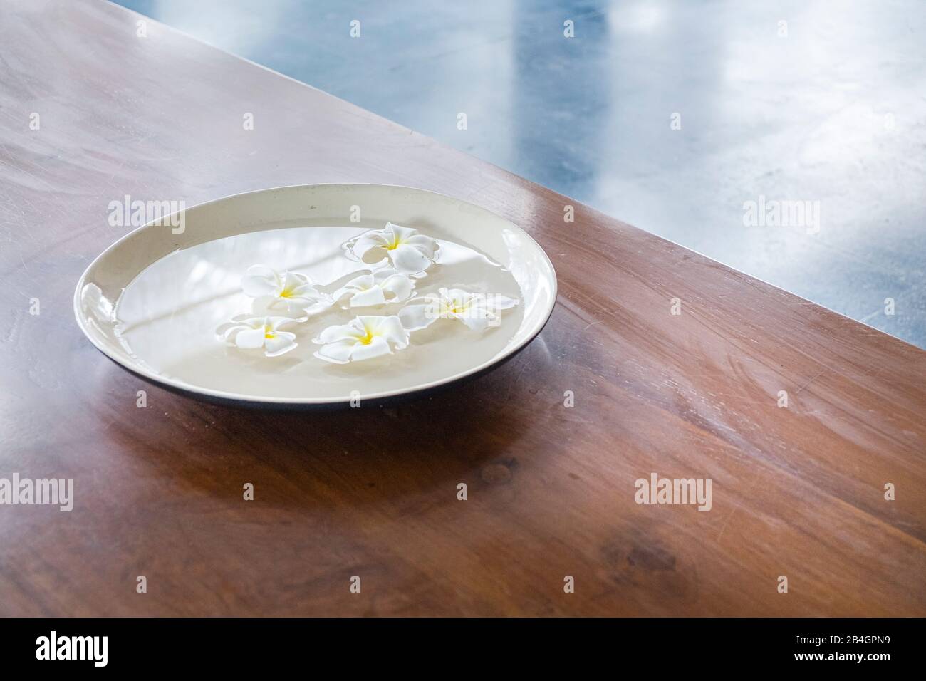 Fleurs dans une tasse d'eau sur table en bois Banque D'Images