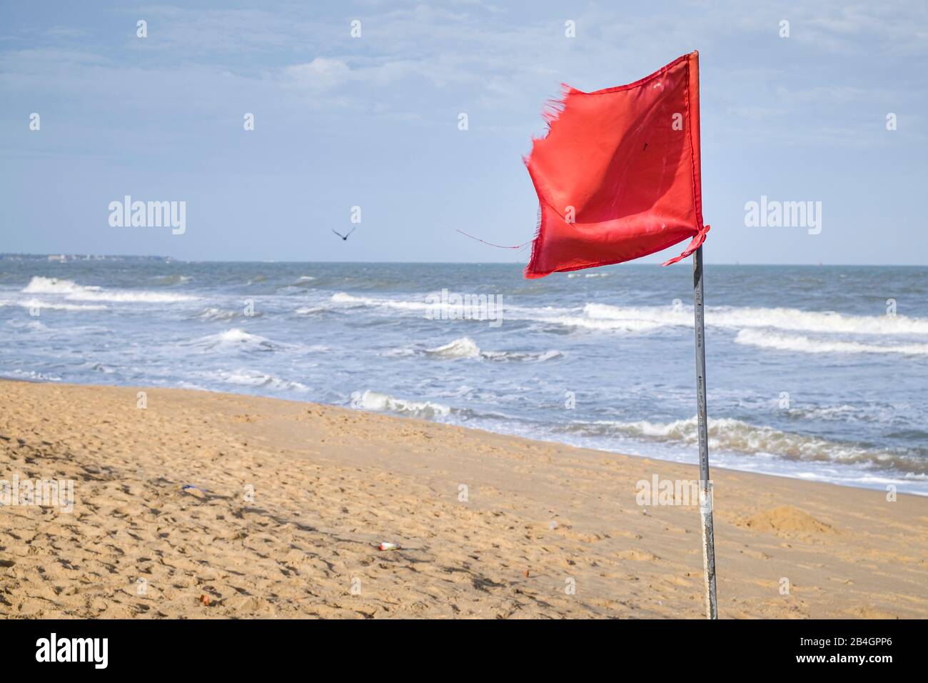 un drapeau rouge sur la plage souffle dans le vent Banque D'Images