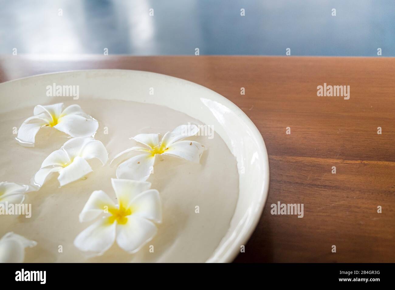 Fleurs dans une tasse d'eau sur table en bois Banque D'Images