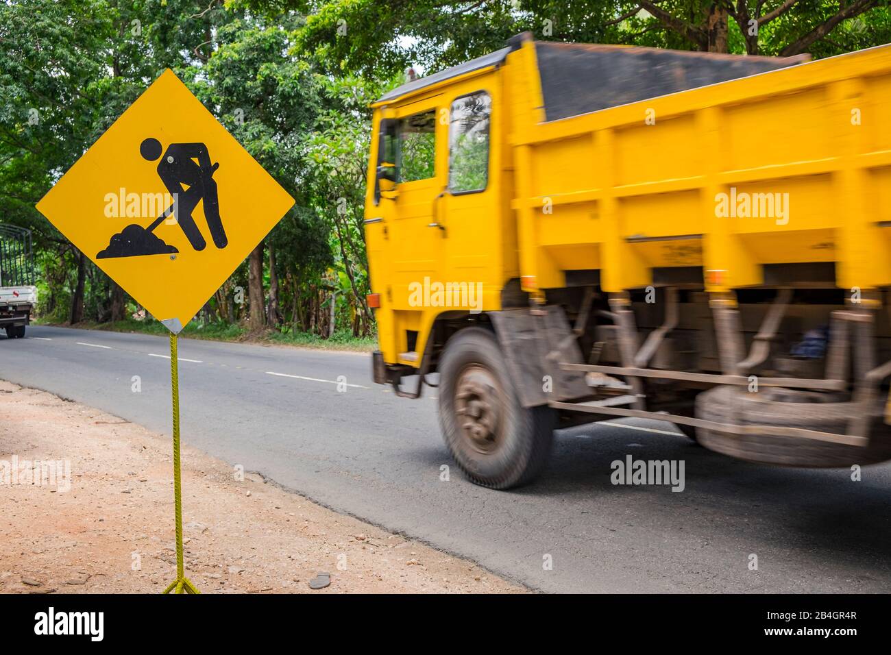 un camion jaune conduit sur la route au panneau du chantier Banque D'Images