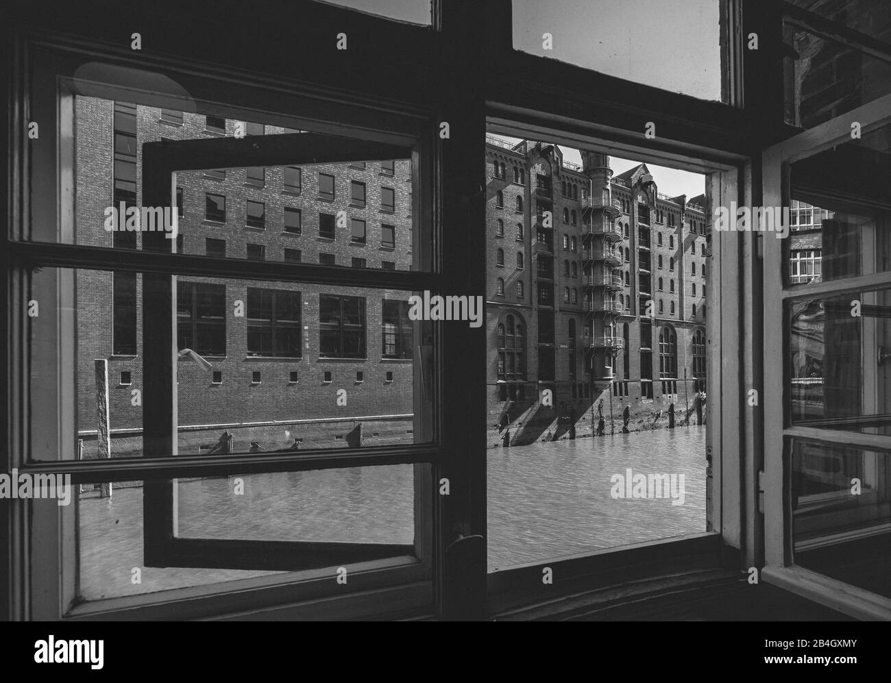 Vue sur l'historique Speicherstadt et Fleet à travers une vieille fenêtre, Hambourg, Allemagne, site classé au patrimoine mondial de l'UNESCO, urbain, noir et blanc Banque D'Images