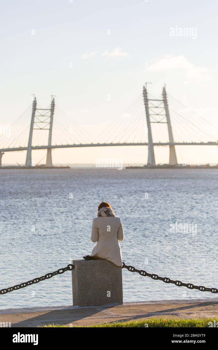 Solitude, désir d'être seul, promenade le long de l'eau. Femme assise par mer, en regardant le pont. Vue de l'arrière. Banque D'Images
