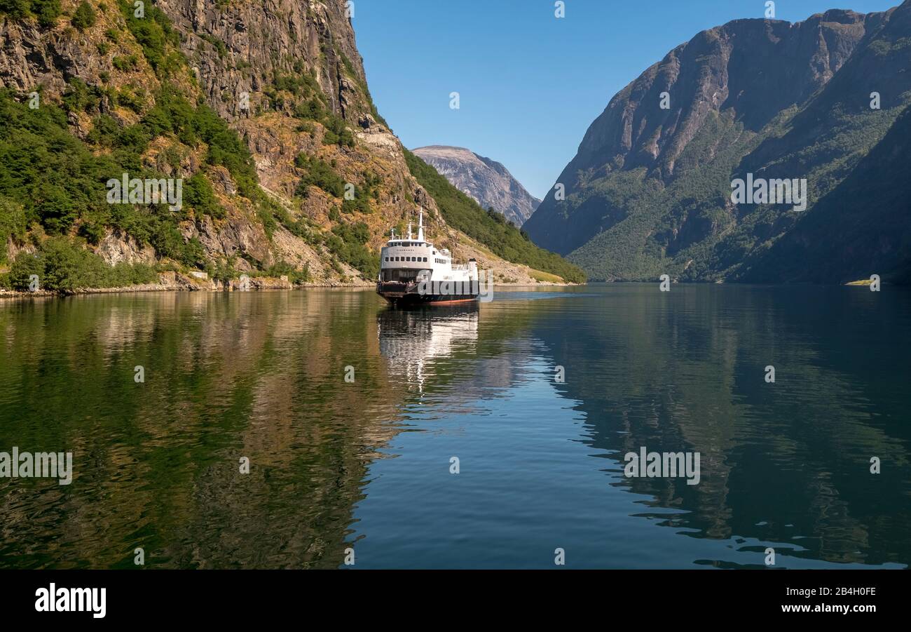 Un bateau de croisière de voile sur un beau fjord dans lequel reflète la lumière, entouré de rochers qui sont partiellement surcultivés avec des arbres, au-dessus d'un ciel bleu vif. Gudvangen, Sogn Og Fjordane, Norvège, Scandinavie, Europe Banque D'Images
