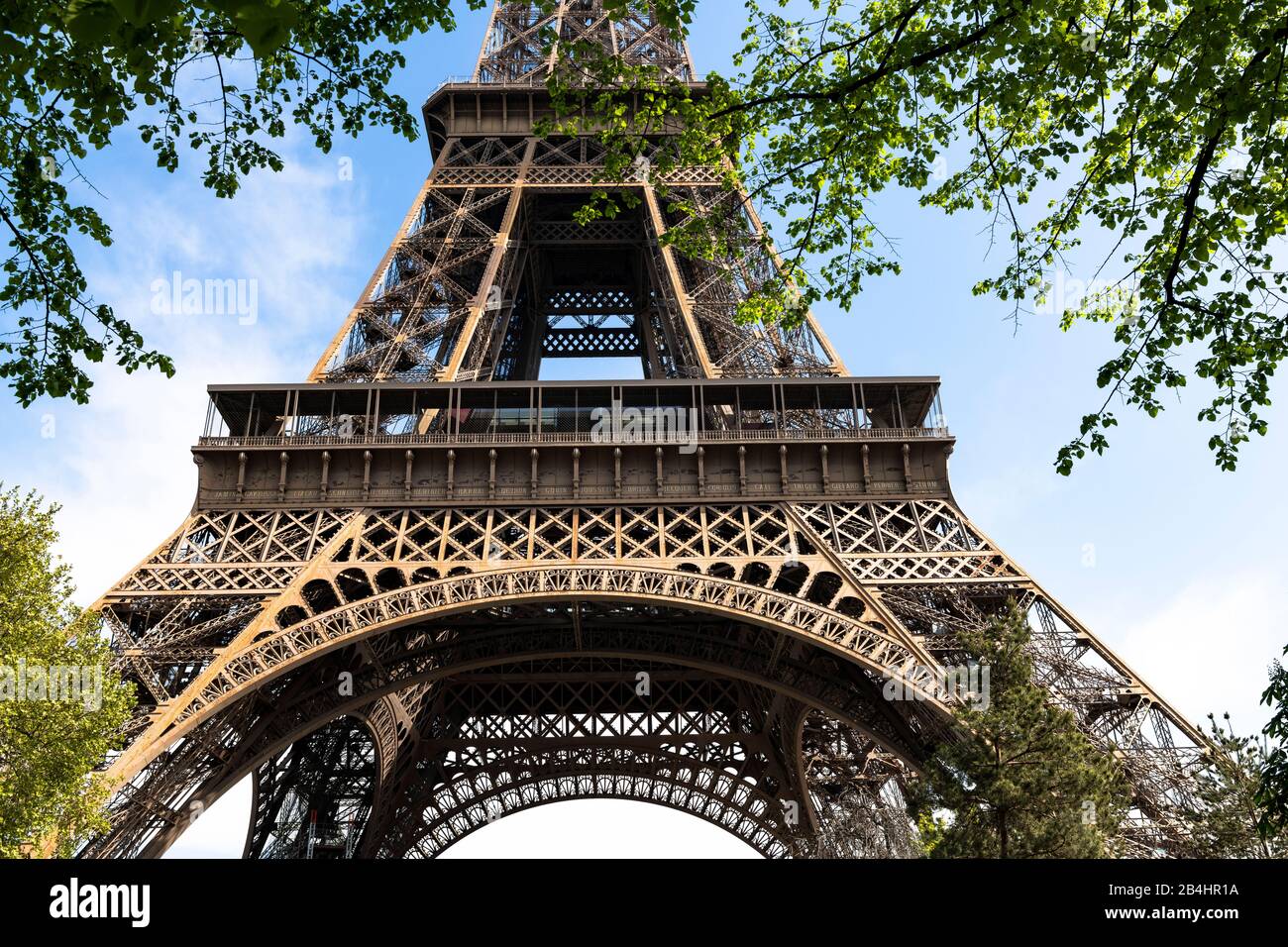 Blick durch Laubbäume auf die untere Besucherebene des Eiffelturms, Paris, Frankreich, Europa Banque D'Images