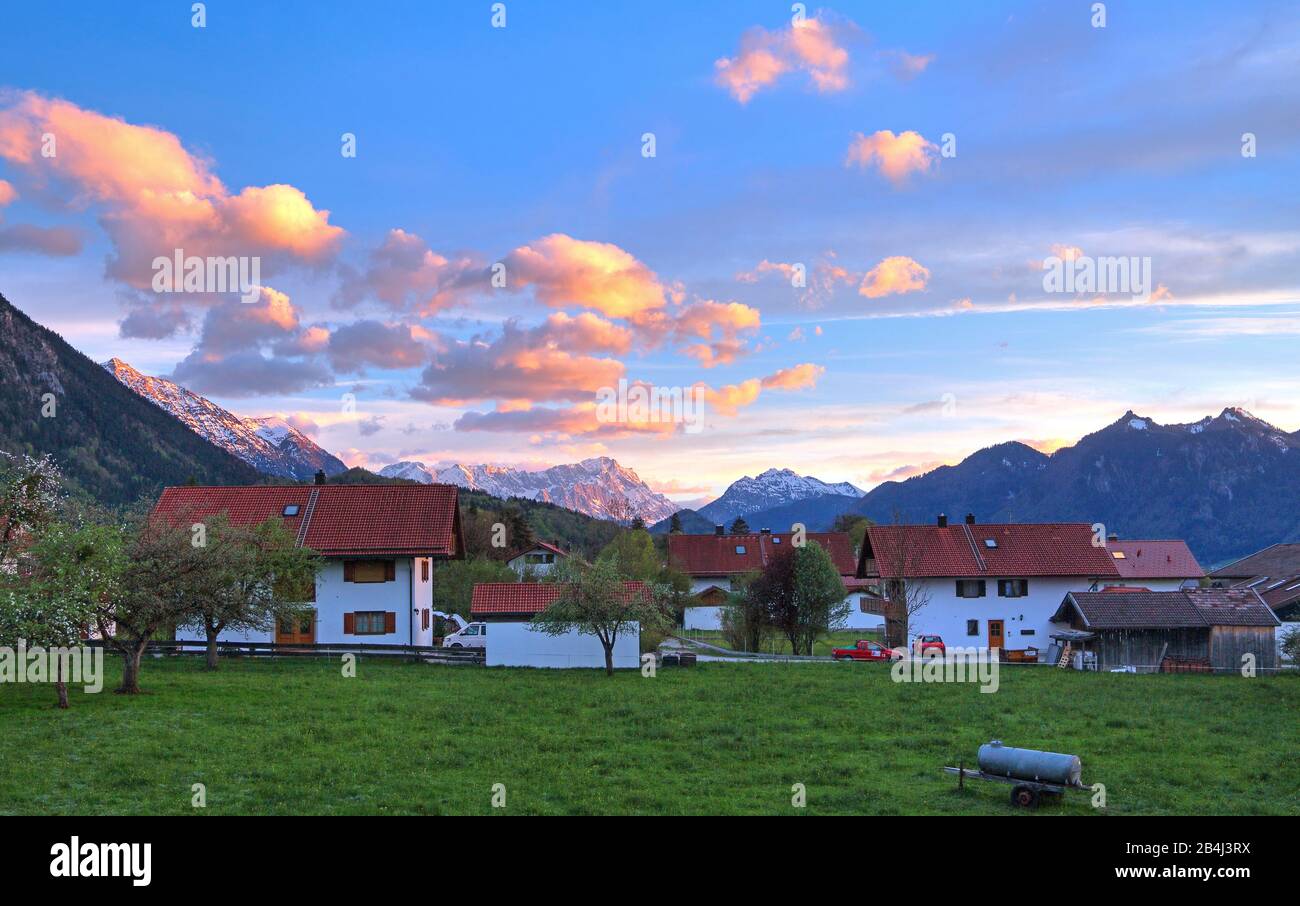 Maisons au bord du village au soleil le soir contre le groupe Estergebirge Zugspitze 2962 m dans les montagnes Wetterstein et les Alpes d'Ammergau, Ohlstadt, Loisachtal, Zugspitzland, Haute-Bavière, Bavière, Allemagne Banque D'Images