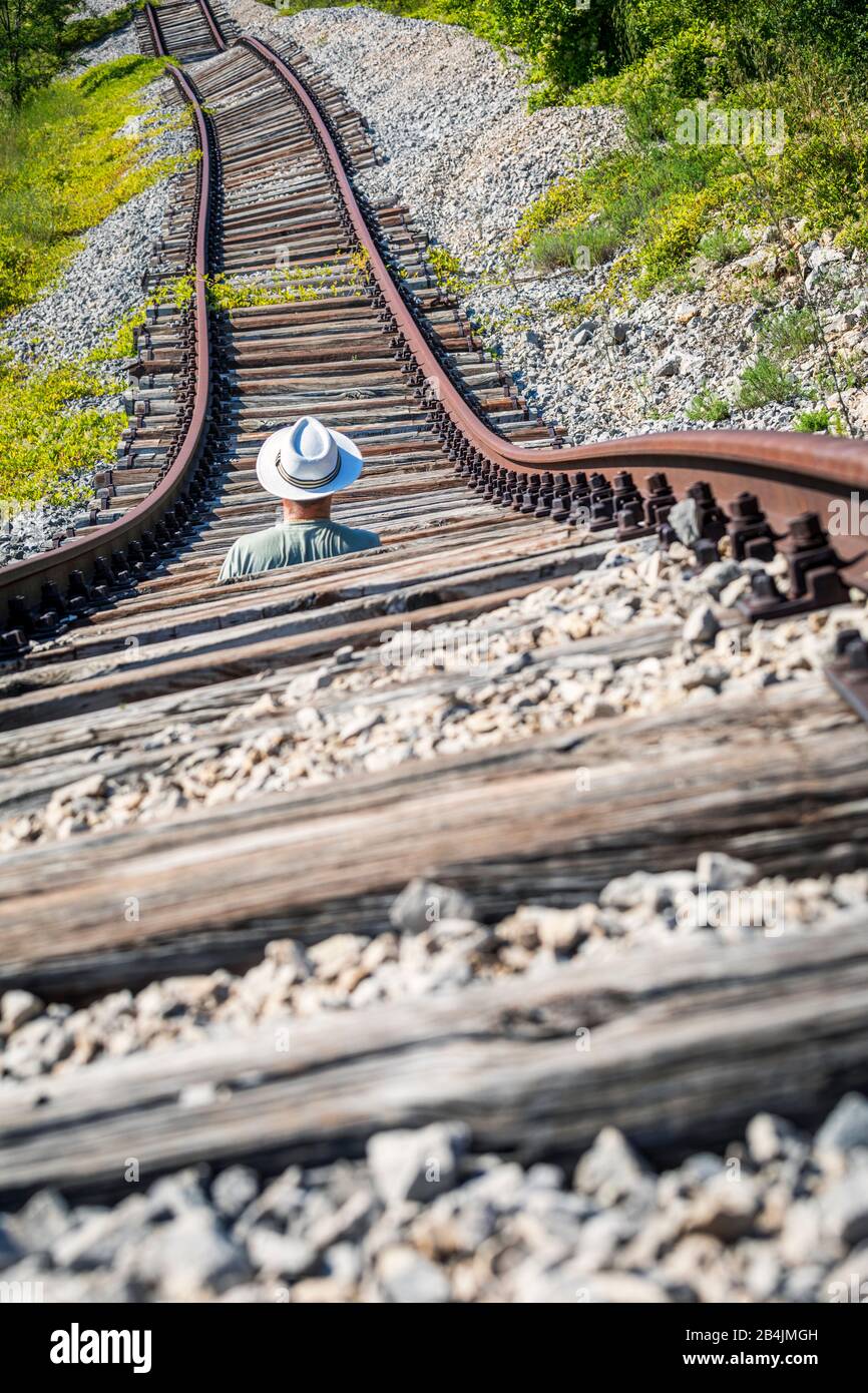 Homme avec chapeau blanc au milieu de rails abandonnés attendant un train imaginaire, Pijana pruga, Kozljak, Krsan, Istria County, Croatie Banque D'Images