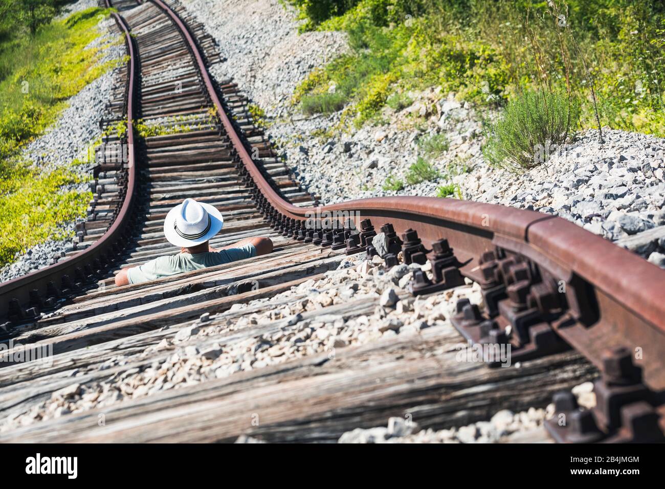 Homme avec chapeau blanc au milieu de rails abandonnés attendant un train imaginaire, Pijana pruga, Kozljak, Krsan, Istria County, Croatie Banque D'Images