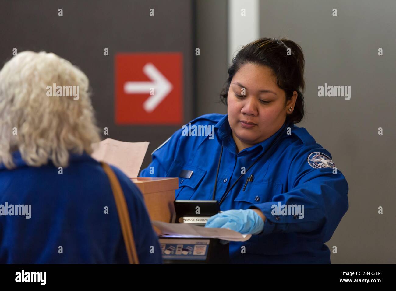 Un agent TSA contrôle un passager à un point de contrôle de sécurité dans le terminal central de l'aéroport international de Seattle-Tacoma le 6 mars 2020. Le port de Seattle s'efforce d'empêcher la propagation du coronavirus par des protocoles d'hygiène élevés et la dotation en personnel des employés de la santé publique qui surveillent de manière proactive les signes de maladie des passagers. Banque D'Images