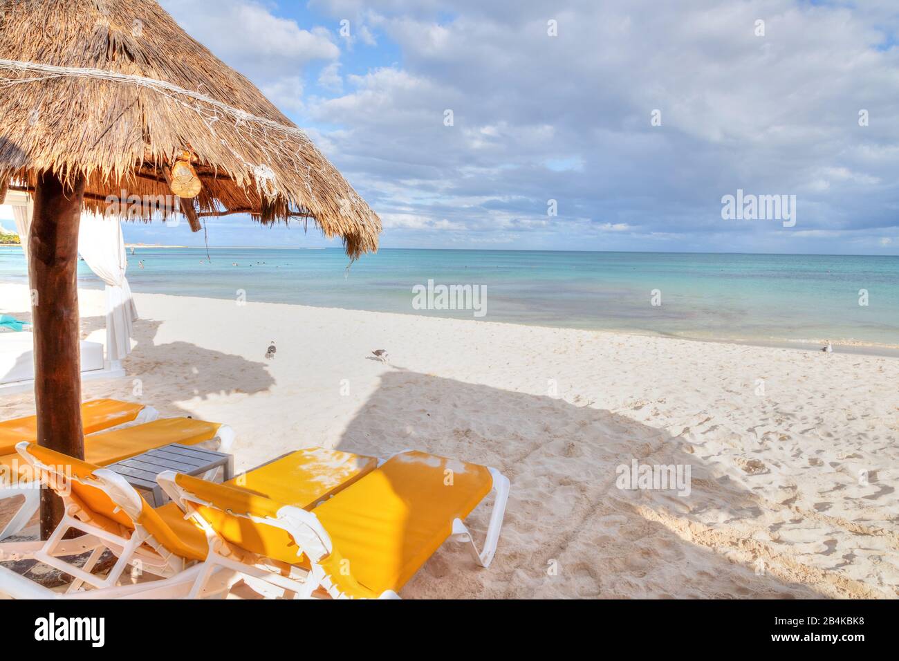 Parasol et chaises longues de plage de paille de palmier à noix de coco sur la plage de sable blanc de la côte des Caraïbes de Riviera Maya, Cancun, Mexique. Banque D'Images
