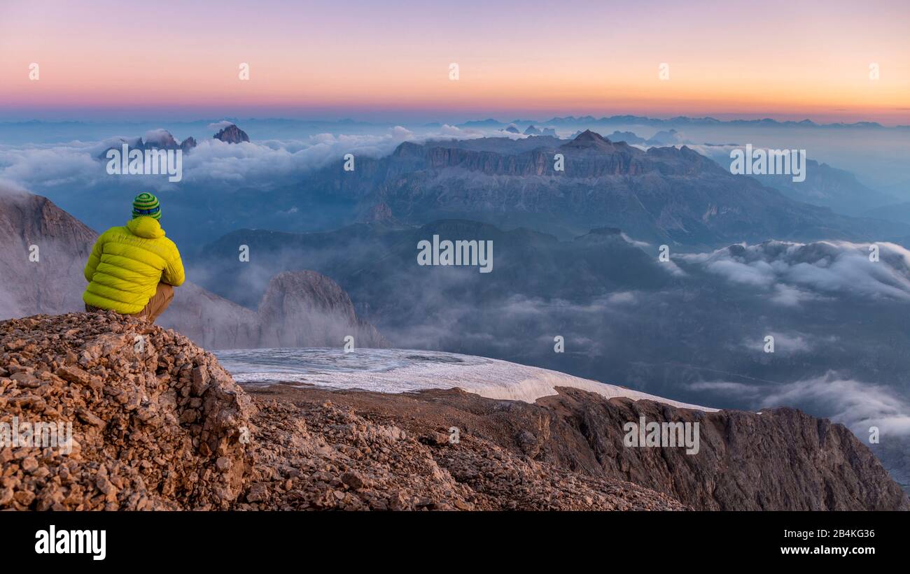 Mountaineer admire le paysage de montagne au lever du soleil à partir d'un éperon rocheux près de Punta Penia, Marmolada, Belluno et trente, Dolomites, Italie Banque D'Images