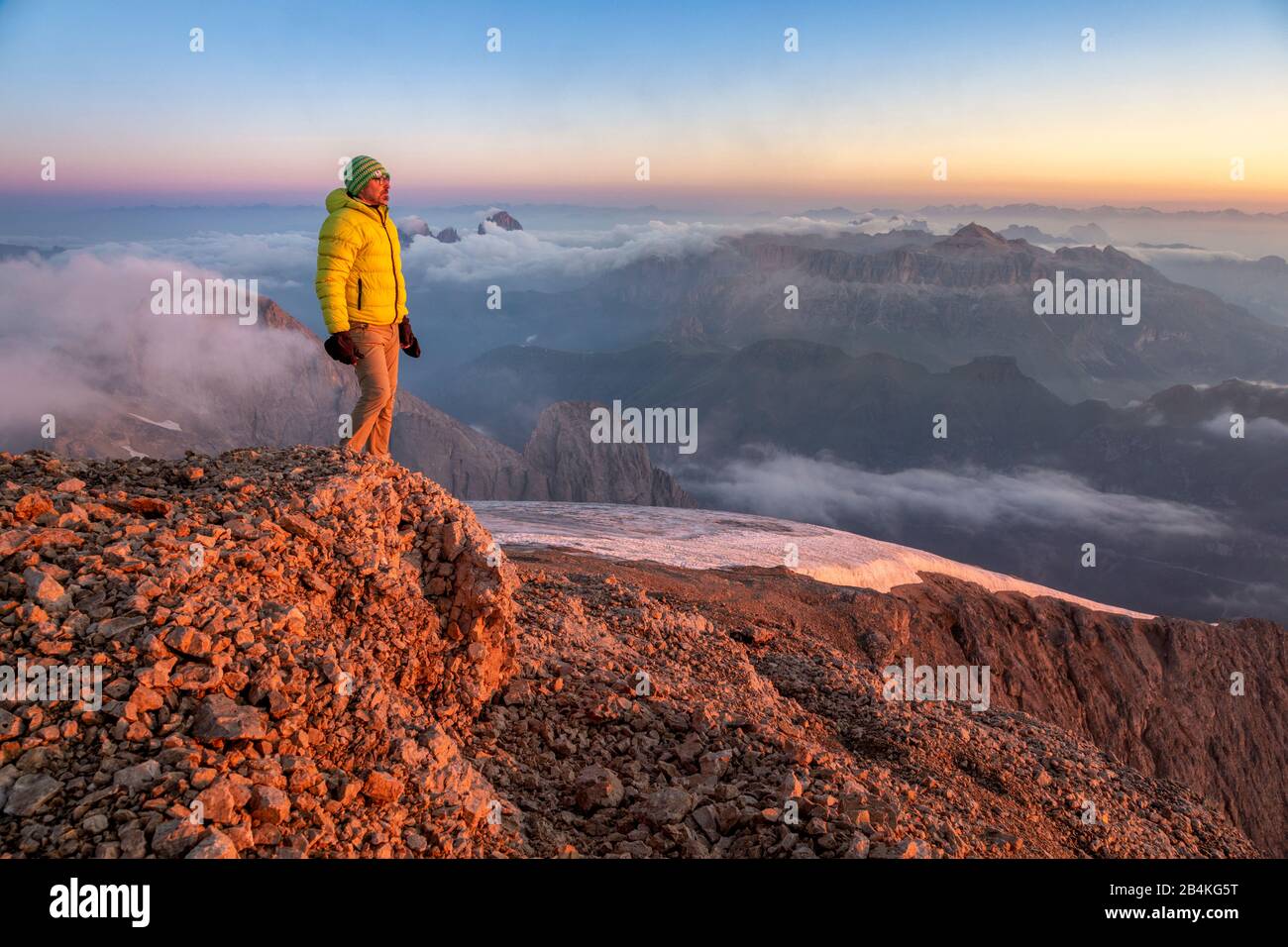 Mountaineer admire le paysage au lever du soleil à partir d'un éperon rocheux près de Punta Penia, Marmolada, Belluno et trente, Dolomites, Italie Banque D'Images