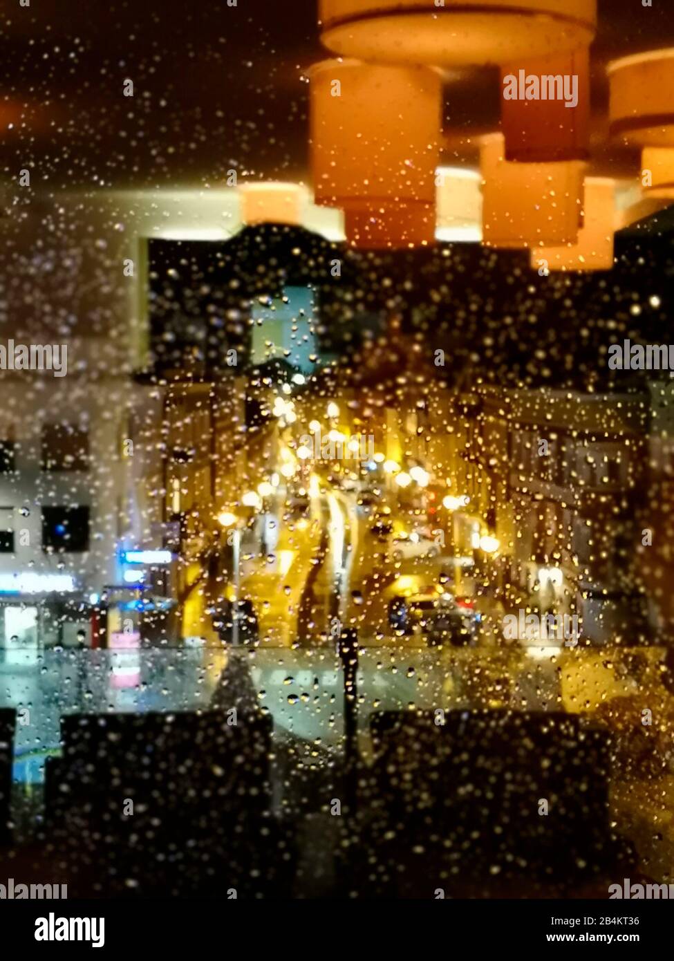 Feux de rue derrière les fenêtres pluvieuses et reflet de l'éclairage intérieur Banque D'Images