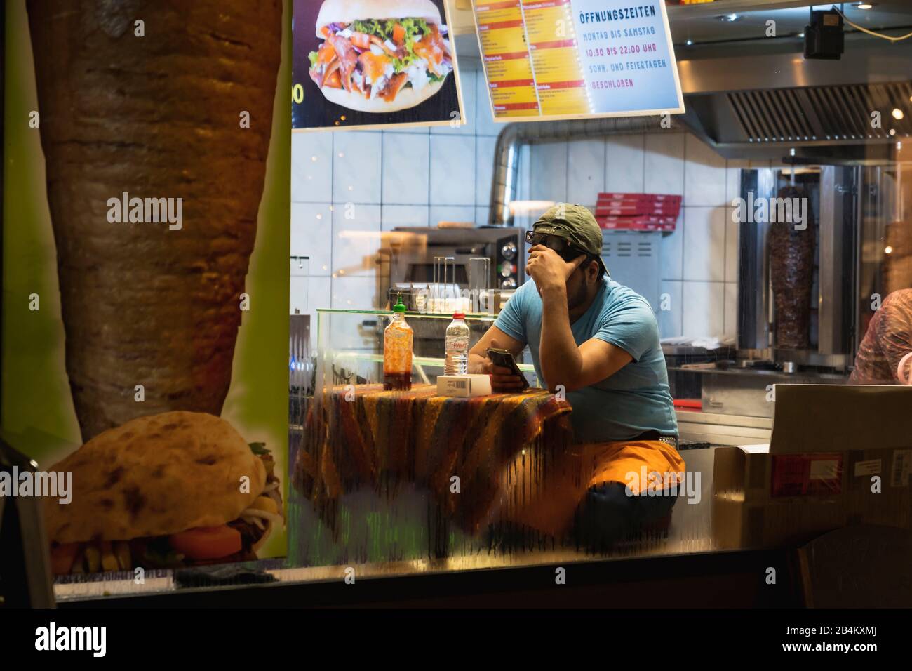 Utilisateur de smartphone dans la boutique kebab, photographie de rue, Allemagne Banque D'Images
