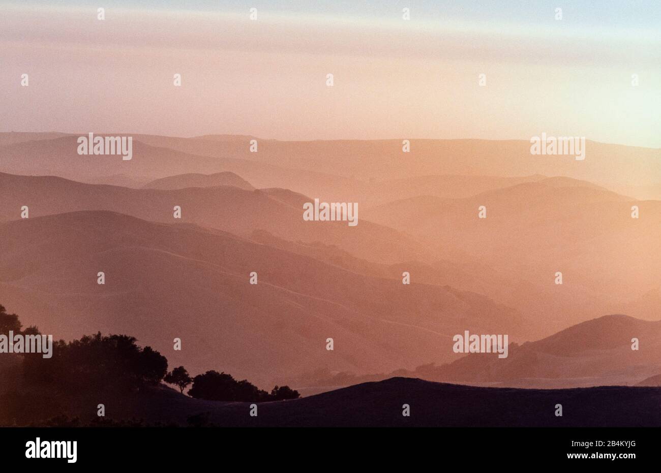 Coucher de soleil brumeux des collines californiennes : lorsque le soleil se couche sur la campagne vallonnée du sud de la Californie, les couches de collines disparaissent au loin. Banque D'Images