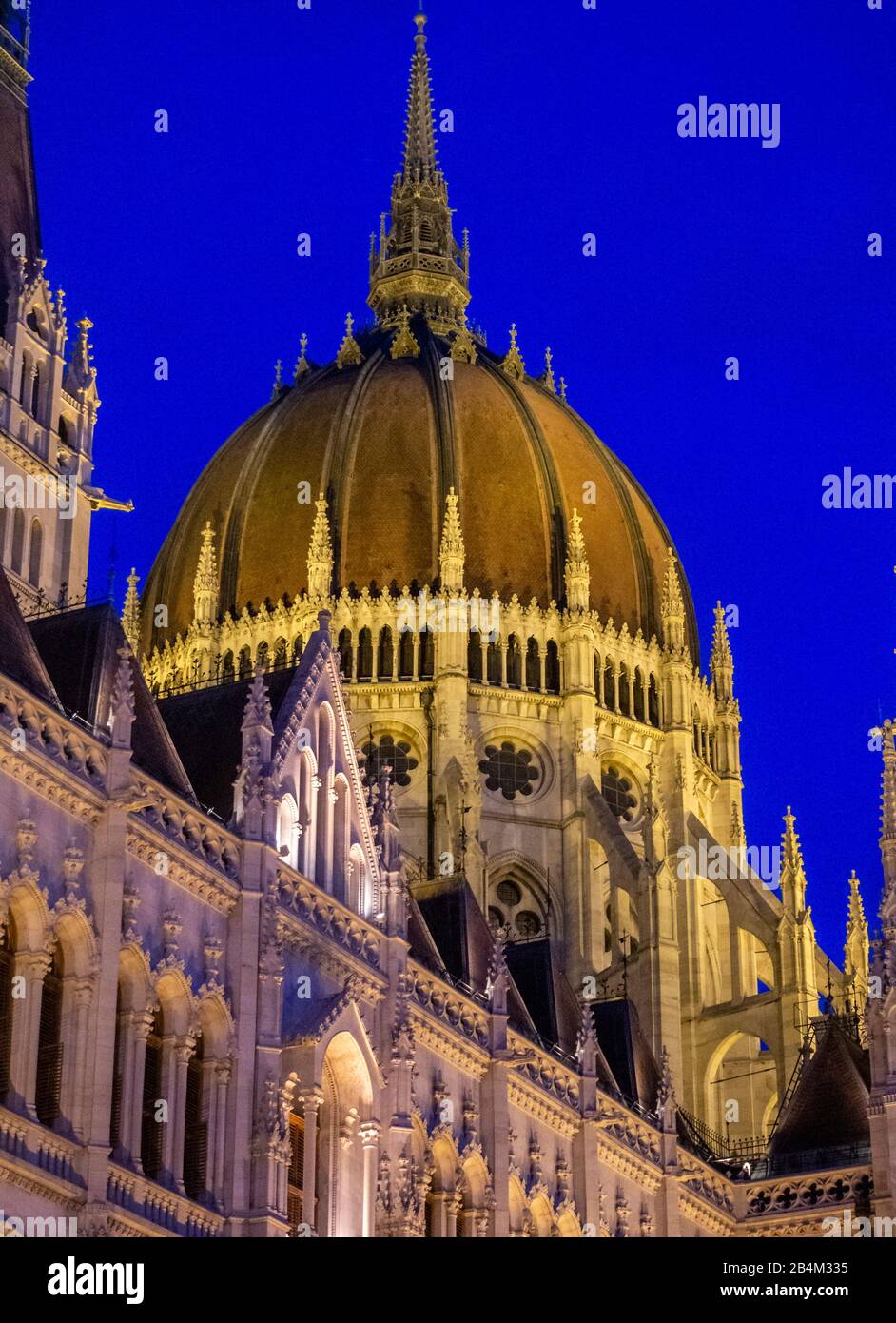 Le dôme central des bâtiments du Parlement hongrois : illuminé au crépuscule, les tours et le dôme des immenses édifices du Parlement hongrois s'illuminent contre le ciel bleu foncé de nuit. Banque D'Images