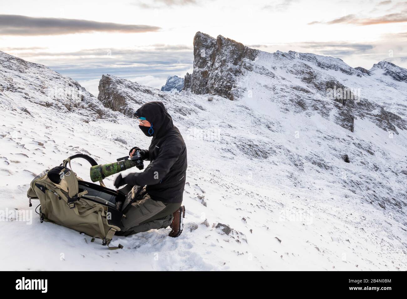 Photographe de nature autoportrait dans les hautes montagnes du Karwendel en début d'hiver, avec neige et vent, l'appareil photo est rangé loin. Banque D'Images