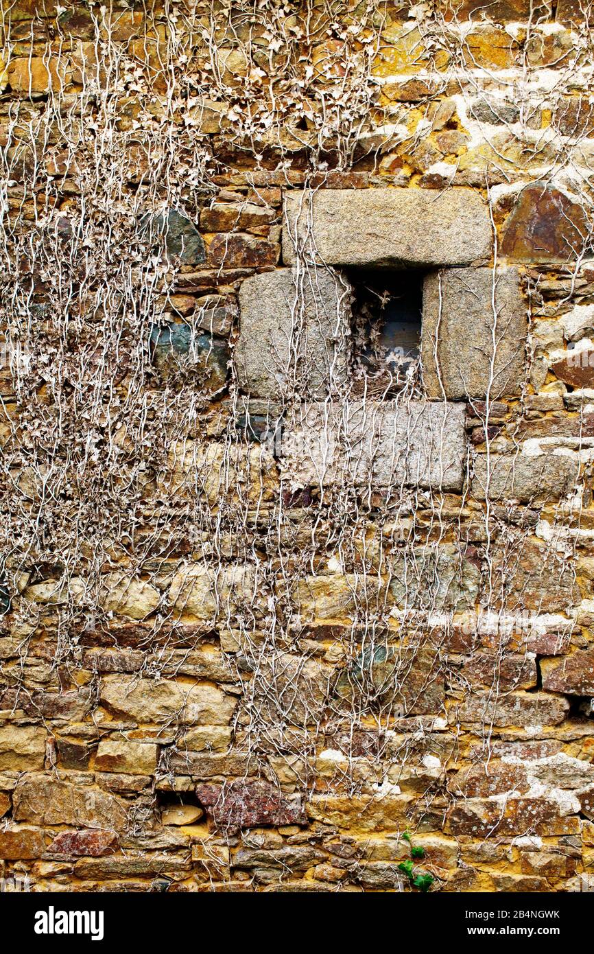 Une petite fenêtre s'ouvre dans un mur rustique en pierre. Runan est une commune française, située dans la région Bretagne des Côtes-d'Armor et compte 233 habitants. Banque D'Images