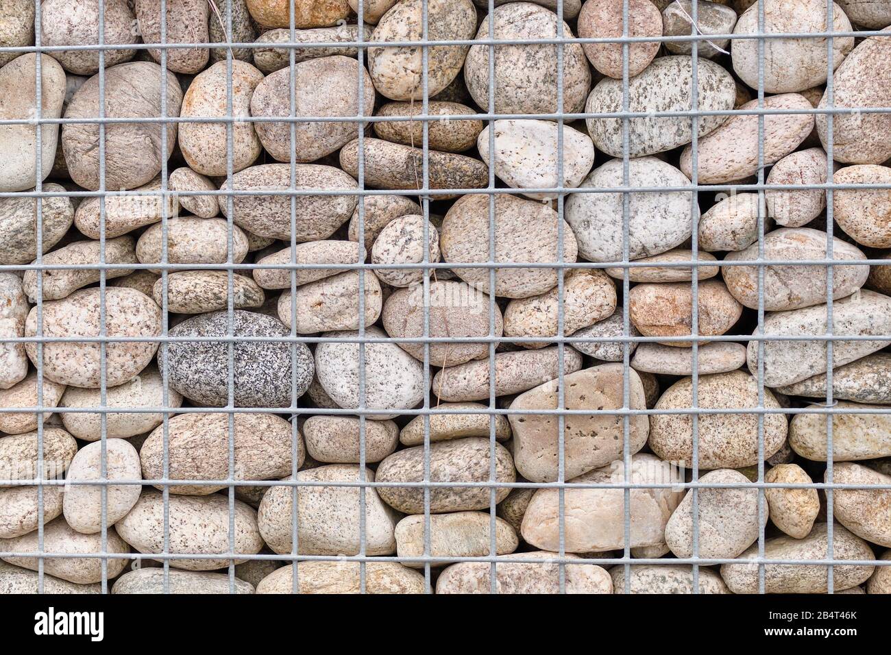 Mur avec pierres lisses dans une grille. Contexte. Gros plan. Banque D'Images