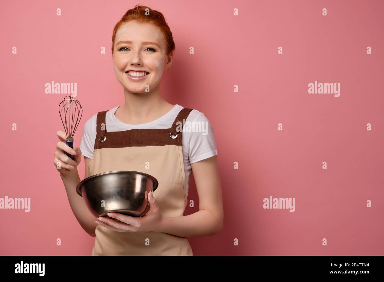 La fille à poil rouge dans un tablier, tachée dans la farine, se tient