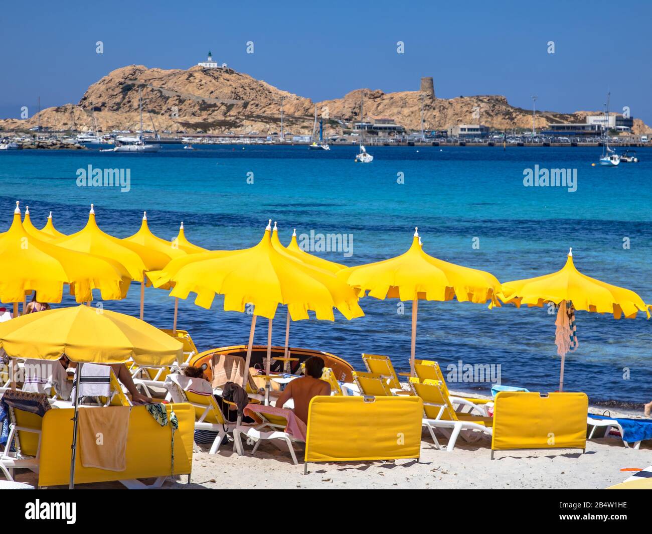 Parasols jaunes sur la plage de la ville d'Ile Rousse sur la côte nord-est de l'île Corse, Calvi, France Banque D'Images