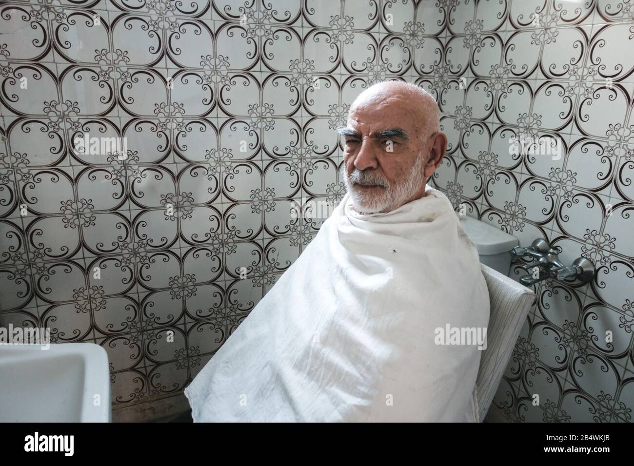 Vieil homme Affamé dans l'appareil photo Tout En attendant sa coupe de cheveux Banque D'Images