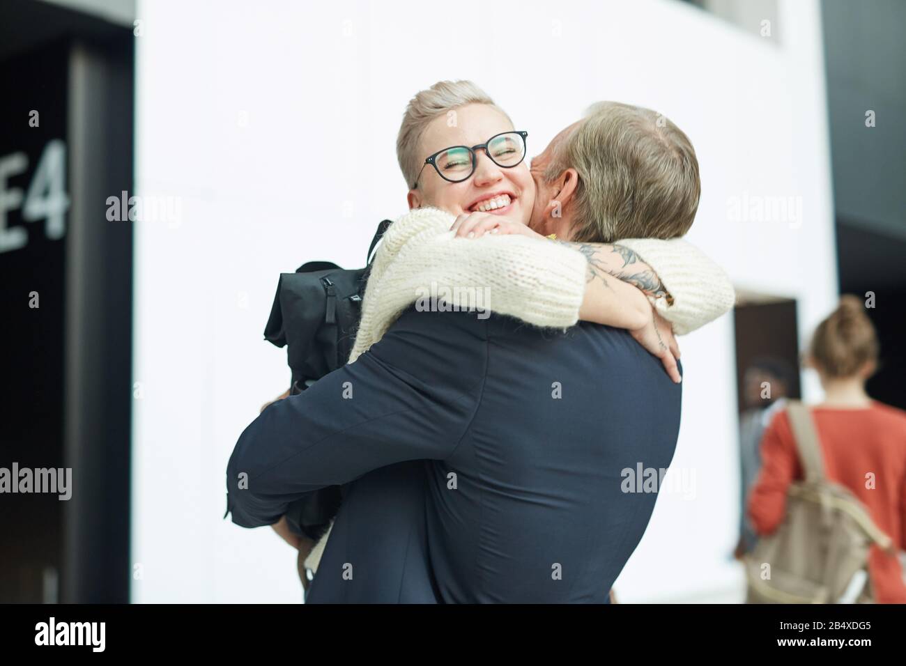 Heureuse jeune femme embrassant son père affectueux, elle n'a pas vu depuis longtemps, à l'aéroport, copier l'espace Banque D'Images